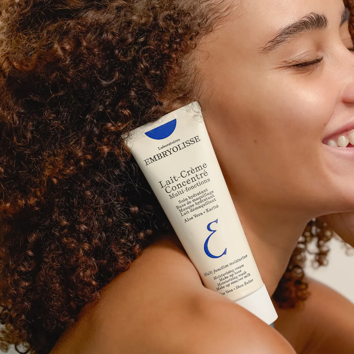 Lait-Crème Concentré tüpünü yüzüne yaslamış gülümseyen bir kadın